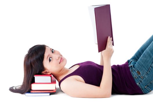 Portrait of an attractive young female lying on the floor with her head resting on books over white baackground