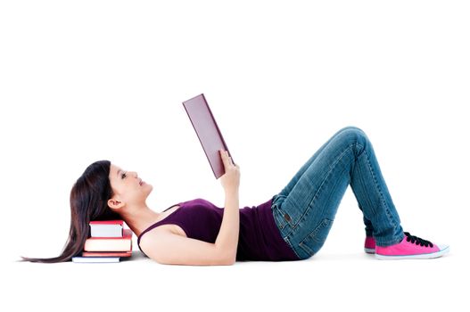 Teenager lying on the floor reading with her head resting on books over white baackground