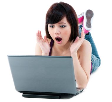 Portrait of a young Asian woman looking amazed at laptop over white background.