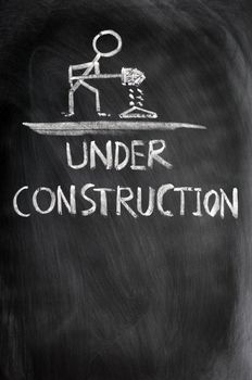 Under construction concept drawn in chalk on a blackboard