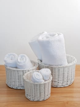 Clean towels in white wicker baskets, on a wooden surface.
