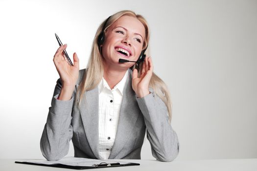 business woman in a headset writing in notebook