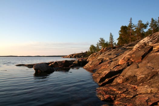 summer sunrise with forest, water and rocks
