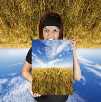 Redhead girl holding a nature canvas. The background is upside-down detoning dreams of travel.

Shot in studio. Composite background.