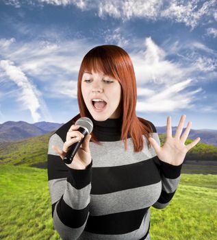 Happy beautiful redhead girl singing on a microphone, karaoke.

Studio shot.