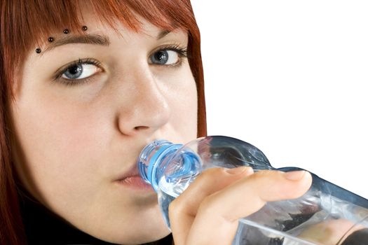Beautiful pierced redhead girl drinking water from a bottle.

Studio shot.