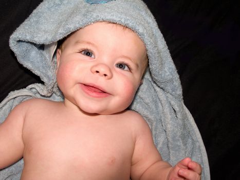 Happy young baby boy  in blue towel