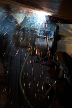 a welder working at shipyard under vessel