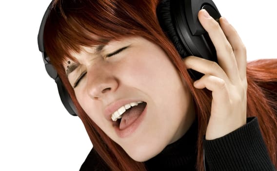 Cute redhead girl enjoying and singing music on her headphones.

Studio shot.