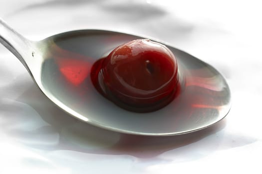 Berry of a cherry in a spoon with juice