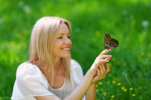 Woman playing with a butterfly on green grass