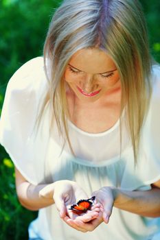 Woman playing with a butterfly on green grass