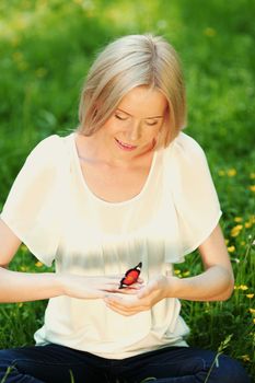 Woman playing with a butterfly on green grass