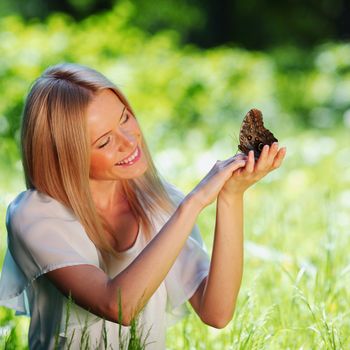 Woman playing with a butterfly on green grass