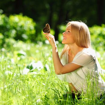 Woman playing with a butterfly on green grass