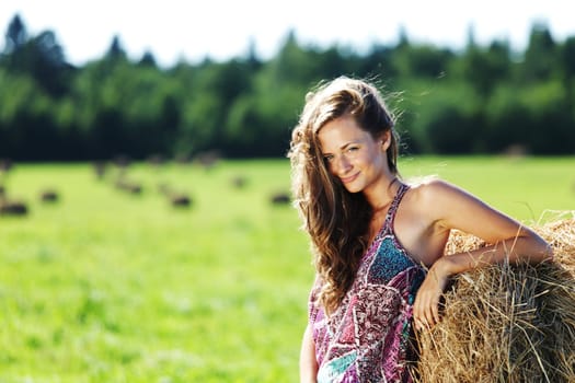 portrait of a girl next to a stack of hay under the blue sky