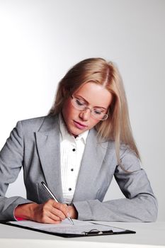 business woman writing in notebook on a gray background