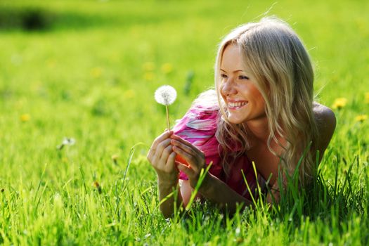 girl with a dandelion in his hand lying on the grass