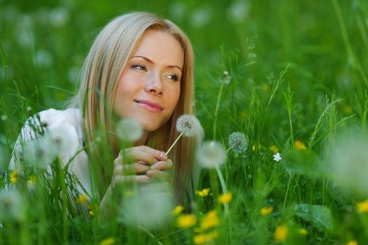 girl with a dandelion in his hand lying on the grass