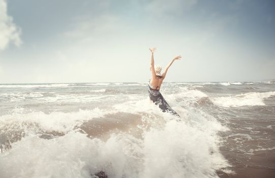 Happy brunette lady in the sea playing with waves