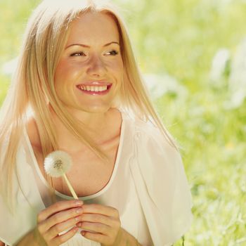 girl with a dandelion in his hand lying on the grass