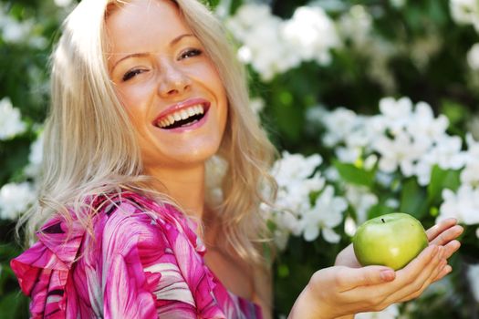 girl with green apple on a background of white flowers