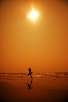 Woman running at the hot beach in the dark night. Artistic red and yellow color toning added