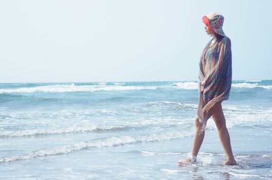 Woman with hat walking at the summer beach. Natural light and colors