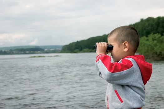 The boy on the river looks in the field-glass