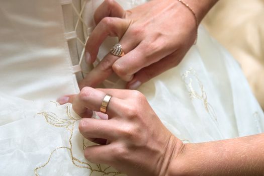 Girlfriends of the bride help to put on a wedding dress