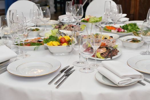 Served table with appetizers, dishes and glasses.