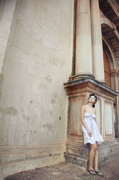 Brunette female tourist looking to the high column of the ancient historical temple. Natural light and colors