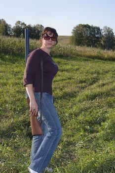 The girl with a gun on a background of an autumn wood