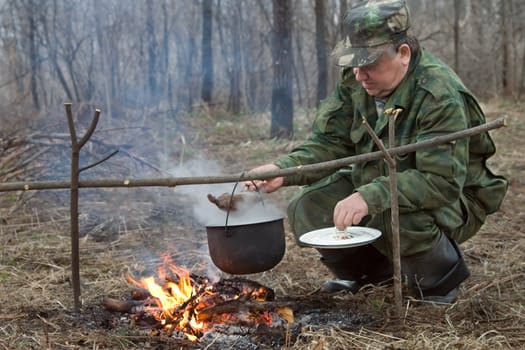 The hunter makes a dinner on a bonfire