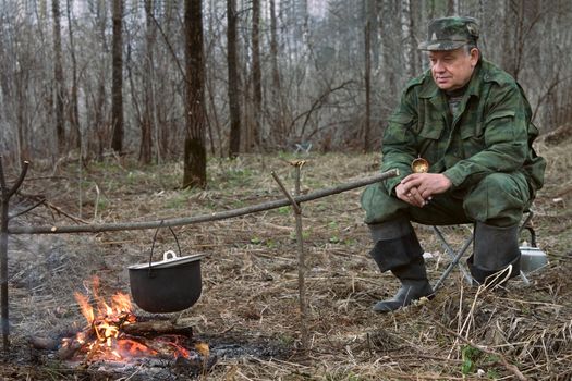 The hunter makes a dinner on a bonfire