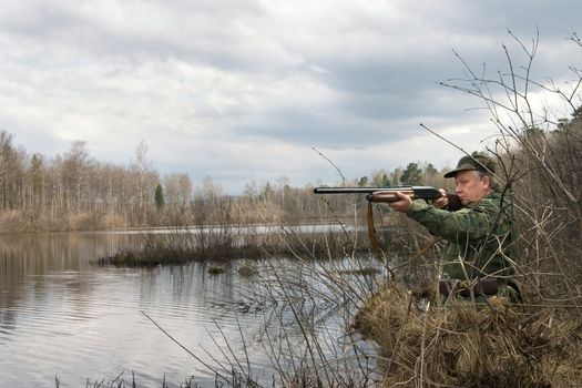 The hunter in a tent aims from a gun