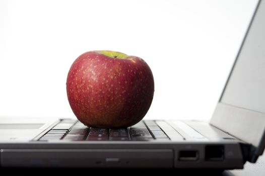 Education concept with an apple resting on an open laptop computer, studio on white
