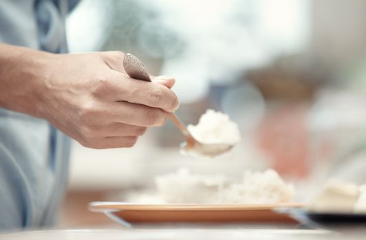 Woman hand holding spoon with rice-milk