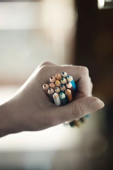 Hand of human holding many pencils. Close-up photo