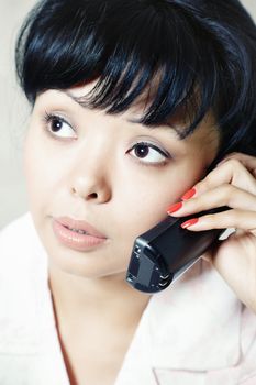 Close-up vertical portrait of the brunette indoors talking via telephone 
