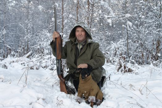 A hunter with a dog in winter forest