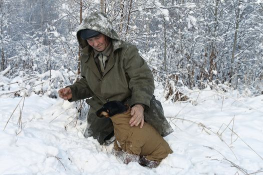 A hunter with a dog in winter forest