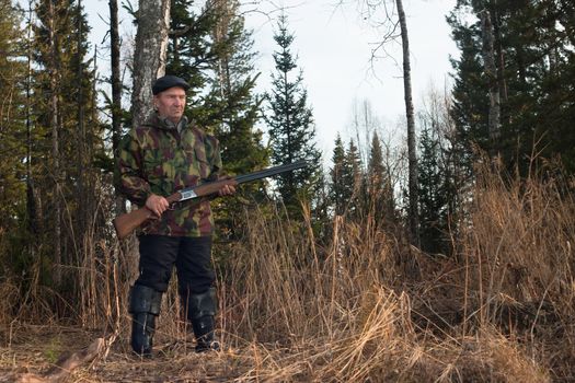 A hunter with a gun in the woods