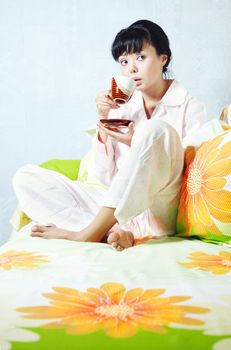 Lady sitting on the bed and drinking coffee