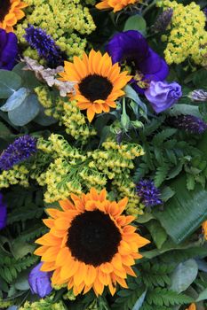 yellow sunflowers and other purple blue flowers in a mixed floral arrangement