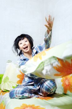 Laughing lady in pajamas playing with pillow