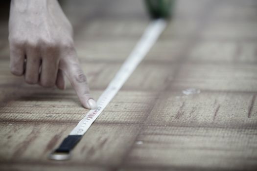Human hands using measuring tape on a wooden surface