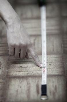 Human hands using measuring tape on a wooden surface