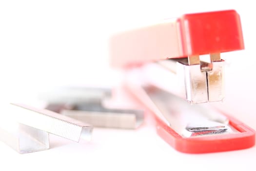 A typicial red stapler sits with staples around it.