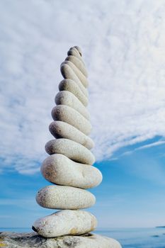 Balancing white pebbles each other on a sky background